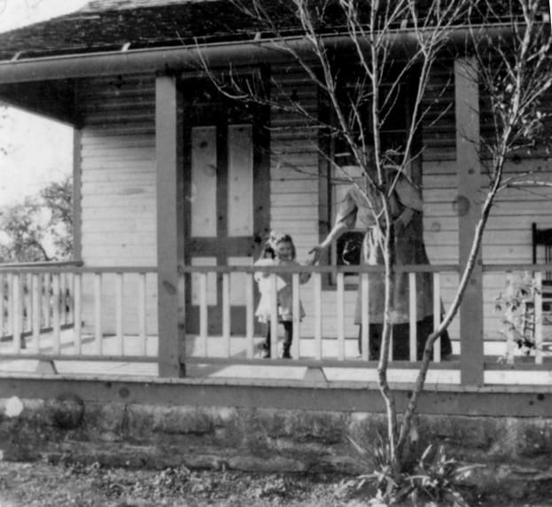 A black and white photo of two people on the porch.